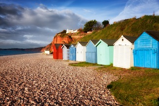 Row of colourful beach huts on the pebble beach at Budleigh Salterton