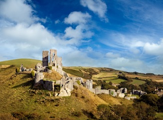 View of Corfe Castle and the surrounding hills on a sunny day