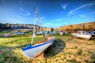 View from inside Mousehole harbour at low tide, looking towards the narrow harbour entrance. Boats in the foreground