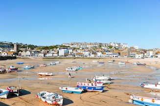 St Ives beach at low tide with boats on the sand and the town in the background