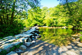 Clapper bridge across the River Barle at Tarr Steps on a sunny summer day