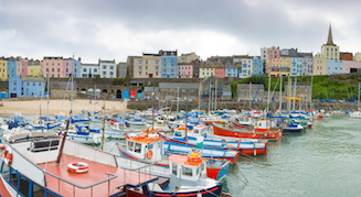 Boats moored in the harbour in Tenby. Colour-washed cottages line the harbour wall