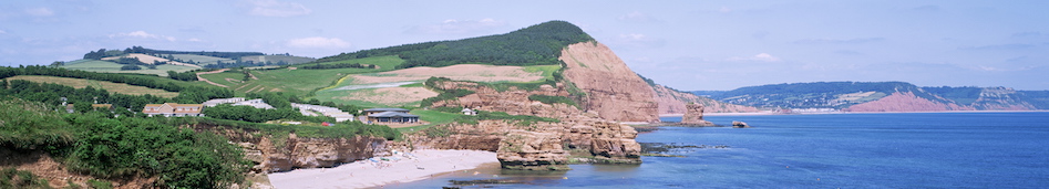 Towering red sandstone cliffs with rolling field inland